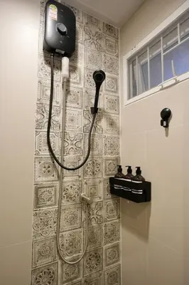 a bathroom with a shower with a blow dryer on a wall at Nivas Wanit 2BR 1SFB Yaowarat MRT EntireHome 80SQM in Bangkok