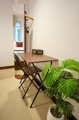 a table and a chair in a room with a plant at Nivas Wanit 3BR 1SFB Yaowarat MRT EntireHome 85SQM in Bangkok