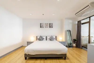 a white bedroom with a bed and a large window at Cozy 2BR Apt in Central Bangkok 5 mins BTS 110 SQM by MattCo in Bangkok