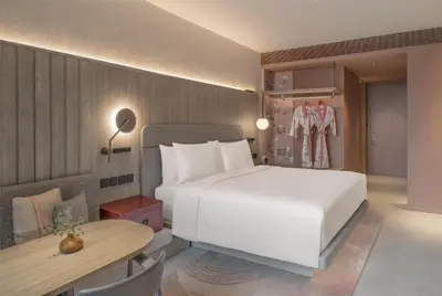 a bedroom with a large white bed and a table at Kromo Bangkok, Curio Collection By Hilton in Bangkok