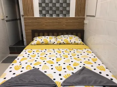 a bed with yellow and white sheets and pillows at 731 Hostel Victory Monument in Sathani Sam Sen