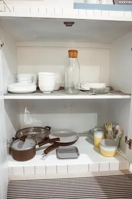 a kitchen shelf with dishes and a glass bottle at Spacious Relaxing Townhouse with Rooftop in Ekamai in Bangkok