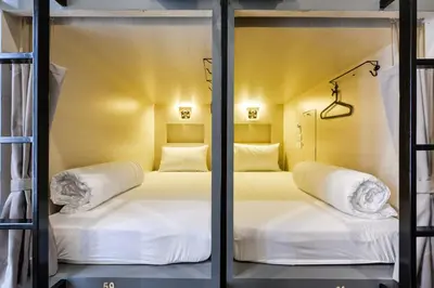 two beds in a room with glass doors at The Cube Hostel Silom in Bangkok