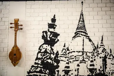 a painting on a white brick wall with a guitar at The Cube Hostel Silom in Bangkok