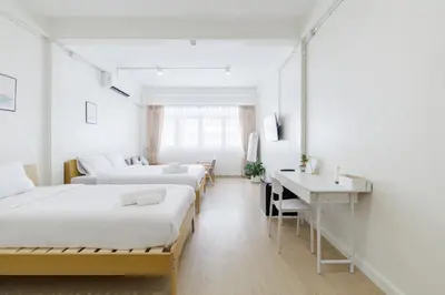 a room with three beds and a desk and a desk at 72 House & Cafe in Phra Khanong
