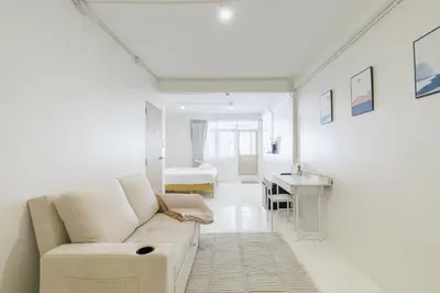 a white living room with a couch and a desk at 72 House & Cafe in Phra Khanong