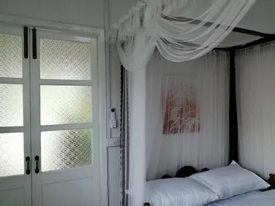 a bedroom with a canopy bed and a window at Baan Chay Klong, Canal side Classic Home 2BRs in Ban Bang Toei (1)