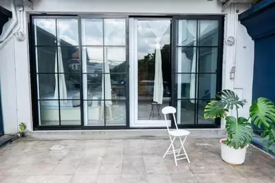 a white chair sitting on a patio with windows at The Local Heritage Loft Mansion in Bangkok