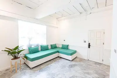 a white room with a couch with green pillows at The Local Heritage Loft Mansion in Bangkok