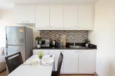 a kitchen with white cabinets and a table with chairs at City Center Nana 4-Guest Suite 100m Nana BTS in Bangkok