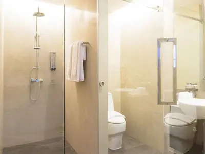 a bathroom with a shower and a toilet and a sink at The Xtreme Suites in Bangkok