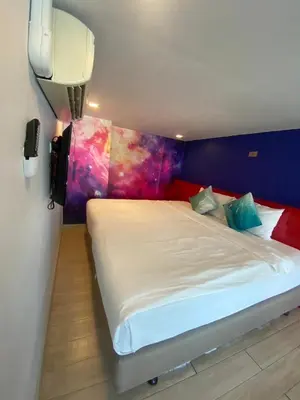 a bedroom with a white bed with a colorful wall at The Xtreme Suites in Bangkok