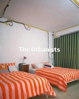 two beds with orange and white striped sheets in a room at The Urbanists BKK Best for groups & long stay near Medpark Hospital , Queen Sirikit Convention hall , Benjakitti Park in Bangkok