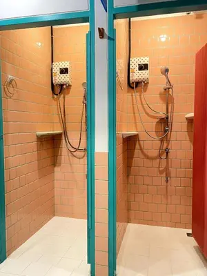 a bathroom with two shower stalls with orange tiles at The Urbanists BKK Best for groups & long stay near Medpark Hospital , Queen Sirikit Convention hall , Benjakitti Park in Bangkok