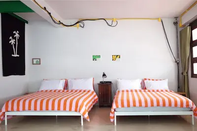 two beds with orange and white striped sheets in a room at The Urbanists BKK Best for groups & long stay near Medpark Hospital , Queen Sirikit Convention hall , Benjakitti Park in Bangkok
