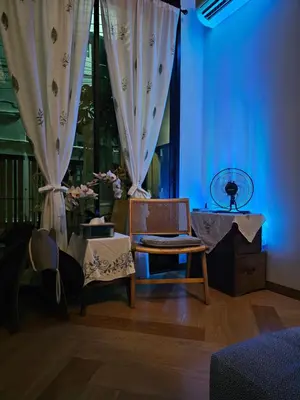 a room with a chair and a table and curtains at hiddenmoon cottage in Bangkok