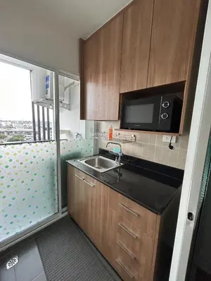 a small kitchen with a sink and a microwave at Charming condo 5min walk to MRT near DMK,Chatuchak in Bangkok