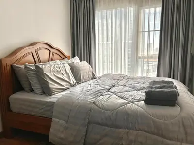 a bed in a bedroom with a large window at Perfect 1BR at MRT Bangson by B in Bangkok