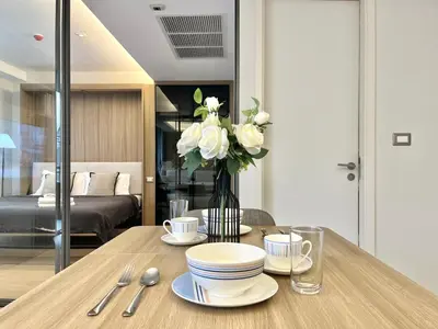 a table with plates and cups and a vase of flowers at Circle 31 #1BR Bangkok in Bangkok