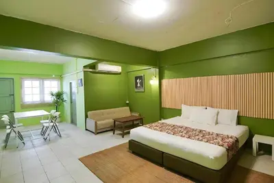 a bedroom with green walls and a bed and a desk at XX GO INN The Grand Palace - MRT Samyot Station in Bangkok