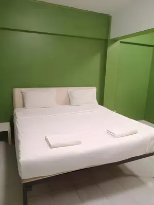 a bed with white sheets and pillows in a green room at XX GO INN The Grand Palace - MRT Samyot Station in Bangkok