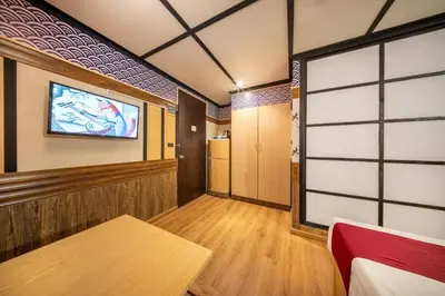 a room with a table and a tv on the wall at SHIN Hotel Victory Monument in Bangkok
