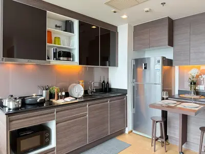 a kitchen with wooden cabinets and a stainless steel refrigerator at Expansive Loft 2BR - Ultra Fast WiFi - BTS Thonglor in Bangkok