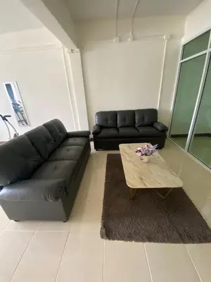 a living room with a black leather couch and a coffee table at Homey Place 2 in Ban Song Hong