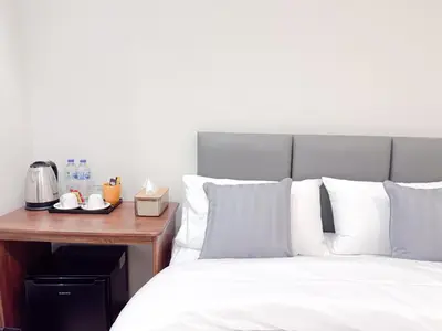 a bed with white pillows next to a wooden table at Vintana Siam Bangkok Hotel in Bangkok