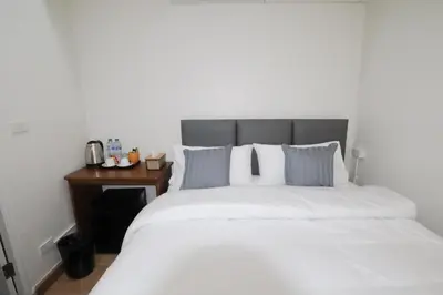 a bedroom with a white bed and a wooden table at Vintana Siam Bangkok Hotel in Bangkok