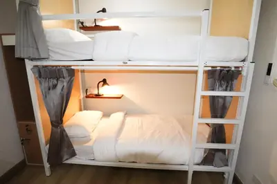 a bunk bed in a room with white beds at Vintana Siam Bangkok Hotel in Bangkok