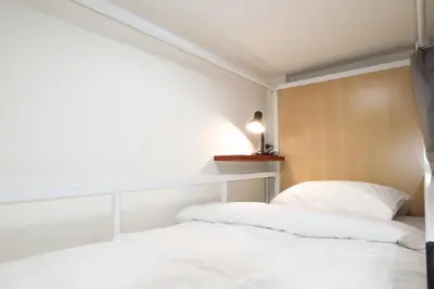 two beds in a room with white sheets at Vintana Siam Bangkok Hotel in Bangkok