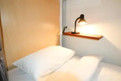 a bedroom with a white bed with a lamp on the wall at Vintana Siam Bangkok Hotel in Bangkok