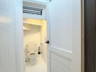 a bathroom with a toilet and a white door at Vélin - Banthat Thong in Bangkok