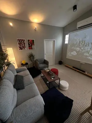 a living room with a couch and a projection screen at Cozy&Modern 6-BR Home, 14pax - Central, 5mins BTS in Bangkok
