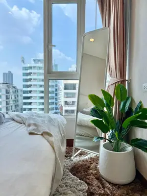 a bedroom with a mirror and a bed and a plant at Luxury Prime Thong Lor - Fast WiFi, Gym&Pool in Bangkok