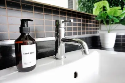 a bottle of hand soap sitting on a kitchen sink at Executive Suite 1BR and Sofa Bed 150m to Nana BTS in Bangkok