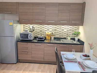 a kitchen with a table and a microwave and a refrigerator at Executive Suite 1BR and Sofa Bed 150m to Nana BTS in Bangkok
