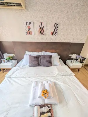 a bedroom with a white bed with towels and flowers on it at Executive Suite 1BR and Sofa Bed 150m to Nana BTS in Bangkok