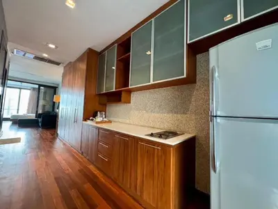 a kitchen with wooden cabinets and a white refrigerator at XX Wish Inn Silom BKK - วิช อินน์ สีลม in Bang Rak