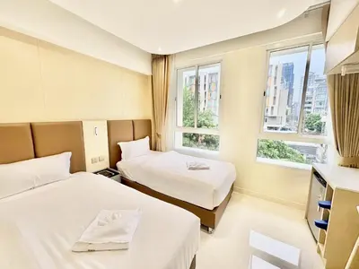 a hotel room with two beds and two windows at ABCQQ Hotel Bangkok in Bangkok