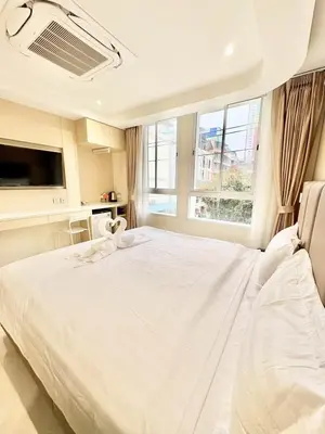 a white bedroom with a large bed and a window at ABCQQ Hotel Bangkok in Bangkok