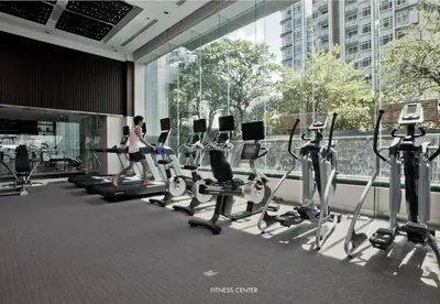 a woman walking in a gym with cardio equipment at The Condo C - Luxury Condo with Onsen in Bangkok