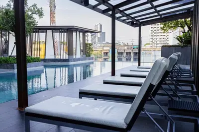 a row of lounge chairs next to a swimming pool at The Elite Club - ThongLor Bangkok in Bangkok