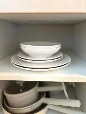 a stack of white bowls and plates on a shelf at The Silent Sanctum in Bangkok