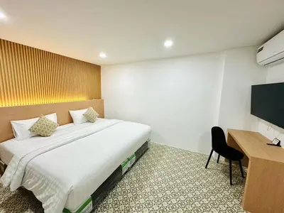 a bedroom with a bed and a desk and a television at The Cozy 77 in Bangkok