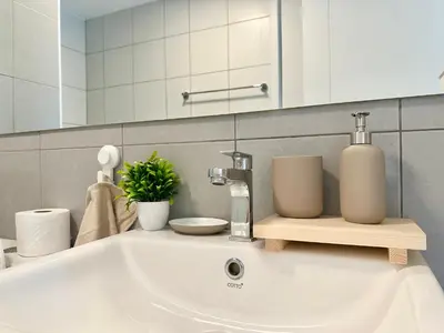 a bathroom sink with a soap dispenser and a mirror at Cosy apartment in Bangkok