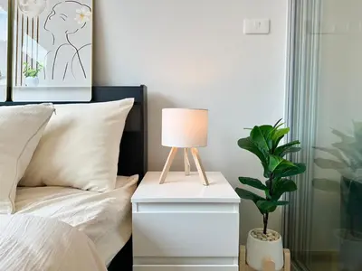 a lamp on a night stand next to a bed at Cosy apartment in Bangkok