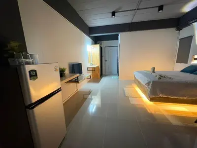a bedroom with a bed and a refrigerator in it at Irich Bang Hua Suae 6kms from BTS Pu-Chao in Ban Bang Chak