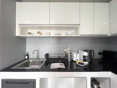 a kitchen with white cabinets and a sink at Modern Cityscape1BR - Ultra Fast WiFi - BTS On nut in Bangkok